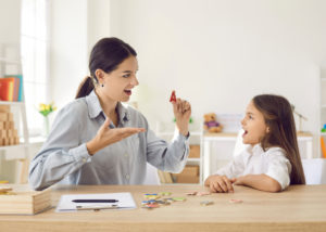 Speech language pathologist helping child learn letters and overcome speech problems