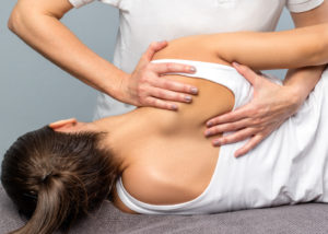 Detail of female therapist manipulating shoulder blade on patient.